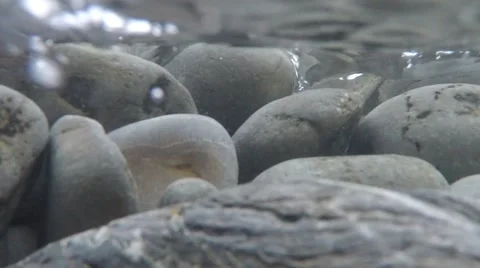 120fps waves washing over round grey pebbles in very clear blue water Stock Footage 47177445