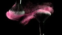 Super slow motion of makeup brushes with powder, black background