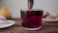 Hibiscus red tea is brewed in a cup on a wooden table.