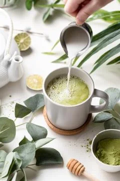 A  vertical  shot  of  Green  tea  latte  with  milk  in  a  white  cup  with  green  leaves  and  wooden  spoon xkwx tea,  green,  latte,  drink,  cup,  beverage,  food,  hot,  milk,  white,  coffee,  background,  cafe,  sweet,  table,  cream,  fresh,  breakfast,  refreshment,  mug,  healthy,  matcha,  japanese,  green  tea,  glass,  cappuccino,  espresso,  liquid,  natural,  chinese,  foam,  morning,  wooden,  wood,  tasty,  powder,  brown,  oriental,  caffeine,  cold,  nutrition,  relax,  cool,  iced,  ice,  organic,  delicious,  smoothie,  nobody,  isolated