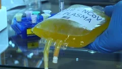 coronavirus laboratory tech handles a IV bag of blood plasma
