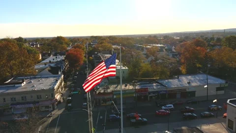 12,928 - Aerial Orbit View of a Large American Flag in the Middle of an Urban Stock Footage 168026693