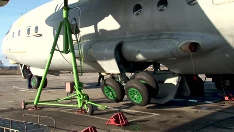 An-12BK on hydraulic lifts. Checking serviceability of landing gear. Close-up. Stock Footage 173393207