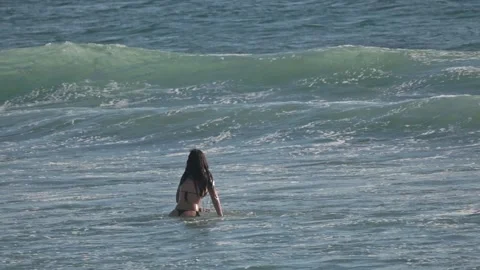 13 April 2025, Costa da Caparica - Portugal - Woman standing in ocean waves Stock Footage 306759994