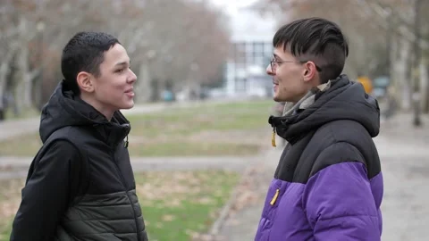 A 13-year-old boy and a young guy are standing on the street, talking and Stock-Footage 169482609