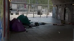Two homeless people sleeping rough in tents under a railway arch in