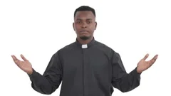Portrait of pacified black priest slowly showing Namaste gesture by raising