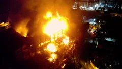 Aerial orbit, drone shot around a burning building. orange fire blazes and