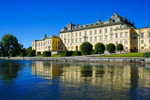 A low angle shot of a river and the Drottningholm Palace in Sweden xkwx palace, landmark, castle, tour, architecture, sky, exterior, park, history, ancient, travel, building, decoration, historical, baroque, garden, city, historic, royal, museum, culture, art, heritage, marble, big, river, water, landscapes, nature, colours, stream, outdoors