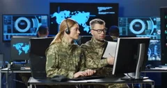 Caucasian couple of military officers in uniforms and headsets sitting at desk