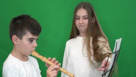 14 a brunette boy in a white jacket plays the recorder, a blonde girl shows Stock Footage 266450696