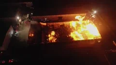 Aerial drone shot of burning warehouse in California, after riots, orange