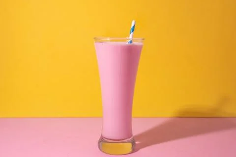 A  glass  of  strawberry  smoothie  isolated  on  yellow  and  pink  background xkwx fruit,  diet,  berry,  strawberry,  drink,  healthy,  nutrition,  food,  fresh,  blended,  vitamin,  milkshake,  background,  summer,  smoothie,  sweet,  dessert,  refreshment,  juicy,  juice,  glass,  pink,  isolated,  straw,  beverage,  horizontal,  yellow