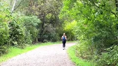 Rear view of women wearing black spandex running alone in the woods on a dir