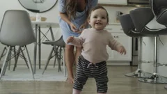 Slow motion of mother applauding baby daughter taking first steps / Bluffdale,