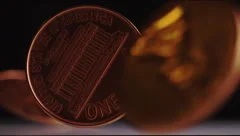 Super slow motion shot of pennies spinning around against a dark background