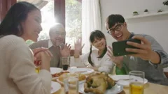 Happy asian family having fun on dining table at home holding mobile