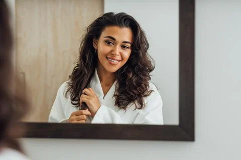 Reflection of a brunette woman in bathroom mirror touching hair xkwx reflection, brunette, woman, bathroom, mirror, touching, lifestyle, refresh, wellness, indoors, home, luxury, leisure, young, beautiful, mixed race, middle east, routine, morning, person, people, smiling, bathrobe, standing, looking, one, real