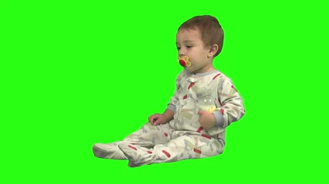 1.5 year old sitting and drinking from bottle. Pajama's. Green background. Stock Footage 49864430