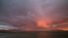 Time lapse of rain storm lighting up during colorful sunset