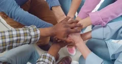 Multiracial people putting hands together in team meeting