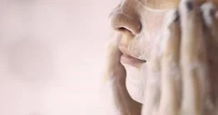 Woman is washing cleaning face with organic foamy soap cleanser, closeup view