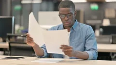 Young African American Man Reading Documents in Office