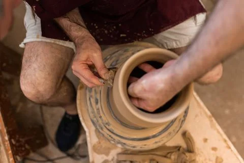 Crop unrecognizable sculptor with equipment giving shape while sculpting with brown clay on throwing wheel xkwx man, shape, clay, sculpt, equipment, process, motion, jug, ceramic, skill, male, sculptor, workshop, art, artist, handicraft, earthenware, ceramist, craft, create, dirty, form, hobby, handmade, maker, master, molding, occupation, pottery, utensil, wet, wheel, professional, work, artisan, throw, small business, talent, workplace, crop, unrecognizable, faceless, anonymous, horizontal, body part, blur, indoors, top view, from above