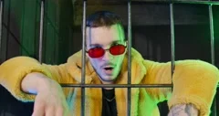 Young guy in glasses with red lenses and yellow faux fur coat hung hands over