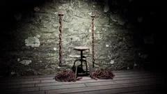 A metal stool tied down by rusty chains in an old dungeon torture chamber.