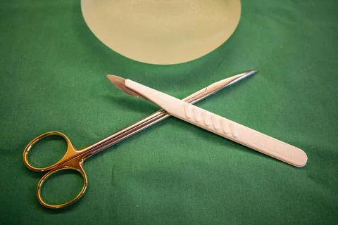 On an operating table are surgical scissors, a scalpel and a silicone ...