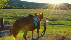 Slender girl leads bay horse under reins