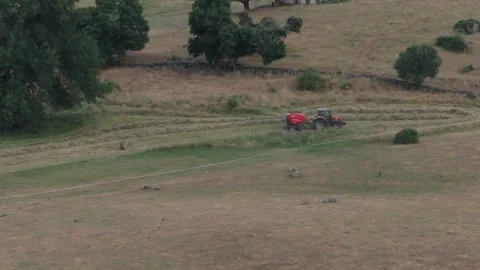 167mm slow motion drone footage of a red farm tractor pulling a red baler Stock Footage 281140625