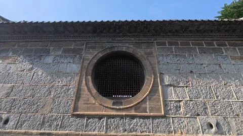 17 ancient stone wall with round lattice window and tiled eaves Stock Footage 345885154