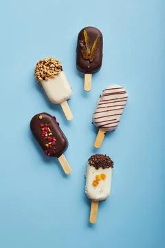 Mousse  dessert  with  fruit  flavors  in  the  form  of  popsicle  ice  cream  covered  with  white  and  dark  chocolate  on  a  blue  background. xkwx ice  cream,  sweet,  mousse,  dessert,  delicious,  food,  cream,  popsicle,  homemade,  lollipop,  cold,  sugar,  stick,  pastry,  party,  pop,  shape,  vanilla,  tasty,  sprinkle,  fruit,  glac,  inside,  flake,  variety,  copy,  cupcake,  filling,  space,  stacked,  assortment,  bright,  cheesecake,  nobody,  closeup,  cookie,  fresh,  plate,  cool,  chocolate,  decoration,  cake,  gastronomy,  meal