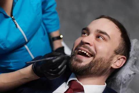 Smiling young man sitting in dentist chair while doctor examining his teeth xkwx medical, woman, man, doctor, dentist, tool, specialist, procedure, patient, oral, gloves, examination, health, treatment, clinic, tooth, teeth, dental, medicine, caucasian, equipment, stomatology, visit, mouth, cabinet, checkup, cure, examine, young, uniform, latex, indoors, orthodontist, sterile, protective, mask, dentistry, hospital, toothache, surgical, instrument, hygiene, workplace, heal, operation, inspection, occupation