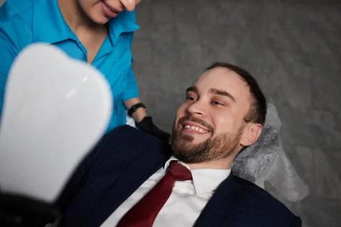 Smiling young man sitting in dentist chair while doctor examining his teeth xkwx medical, woman, man, doctor, dentist, tool, specialist, procedure, patient, oral, gloves, examination, health, treatment, clinic, tooth, teeth, dental, medicine, caucasian, equipment, stomatology, visit, mouth, cabinet, checkup, cure, examine, young, uniform, surgical, protective, mask, toothache, latex, operation, hygiene, orthodontist, occupation, dentistry, workplace, indoors, instrument, sterile, heal, hospital, inspection
