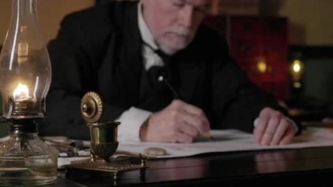 1800s man using a graphite pencil with focus on oil lamp Stock Footage 336746983