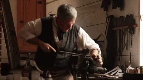 18th Century Colonial Blacksmith working with metal saw on iron bar - Gunsmith Stock Footage 81529642