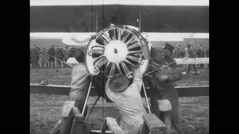 1910s: Army mechanics remove engine rotator from Sopwith Camel plane parked on a Stock Footage 137405391