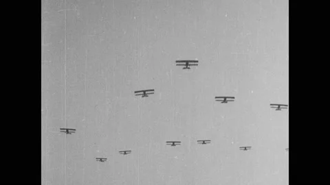 1910s: Biplanes fly in formation through sky. Biplanes fly low over grassy Stock Footage 137405158