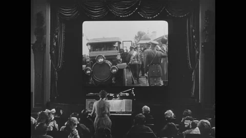 1910s: Movie theater.  Woman plays piano.  Audience.  Film of royal family and Stock Footage