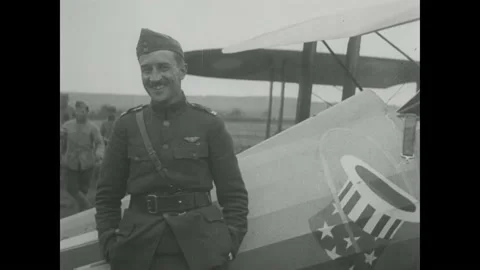 1910s: Pilot looks back while seated in cockpit of plane. Plane in flight. Stock Footage 215919947