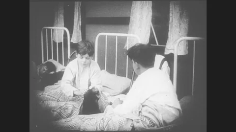 1910s: Schoolgirls and schoolboys get into their respective beds. The two boys Stock Footage