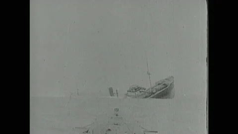 1910s: Ship sinks.  Men on top of submarine.  Submarine fires torpedo at ship.  Stock Footage 137837730