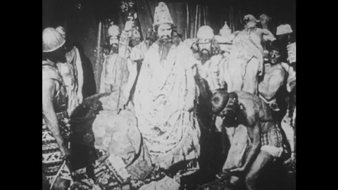1910s: UNITED STATES: man stands by throne. People in street. Guard pulls man Stock Footage