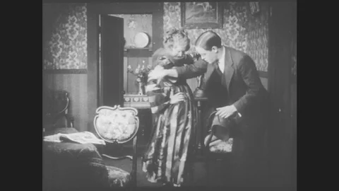 1910s: Young man inspects young woman's dress as she shows it off to him. They Stock Footage
