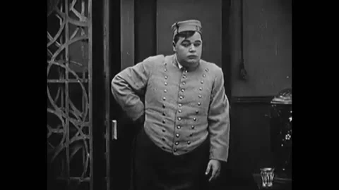 1918 - In this silent comedy, a hotel concierge aggressively rings his bell to Stock Footage 241798973