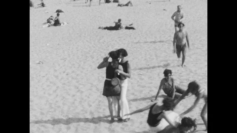 1920s: 2 women dance on beach, woman falls, man runs up, helps girl up from Stock Footage