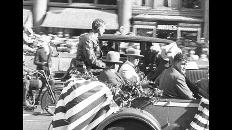 1920s: Charles Lindbergh rides in back of convertible car down street in parade. 動画素材 112457906